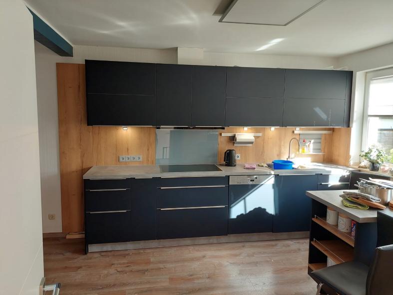 Küche in schwarz mit grauer Arbeitsplatte und Hängeschränken 