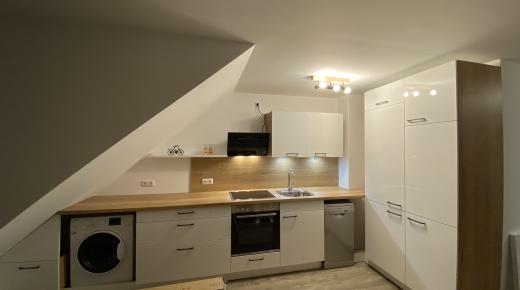 Küche in weiß mit Holzplatte und integrierter Waschmaschine 